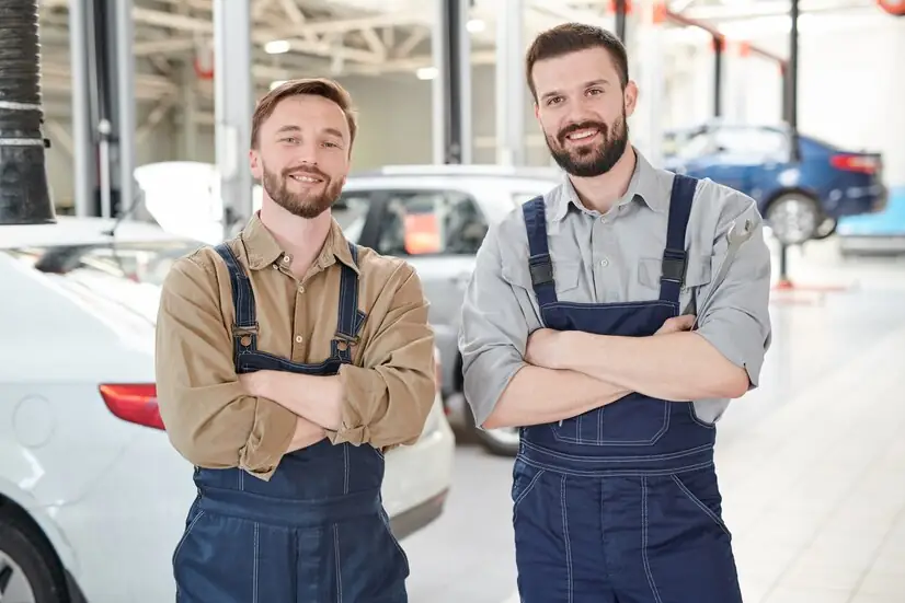 Two friendly car repair gurus working together on a car engine, showcasing the collaborative spirit of CarRepairGuru.com